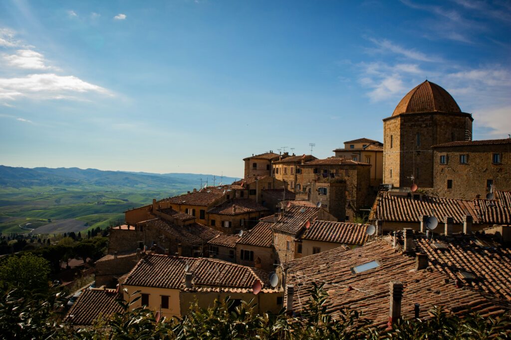 Panoramisch uitzicht over Volterra in Toscane met middeleeuwse gebouwen, terracotta daken en groene heuvels in de verte.